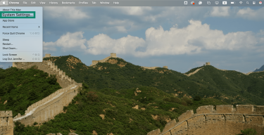 A Mac desktop showing the Apple menu dropdown, with System Settings highlighted.